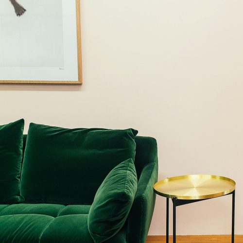 Elegant living room setup featuring a plush green sofa and a chic gold side table.