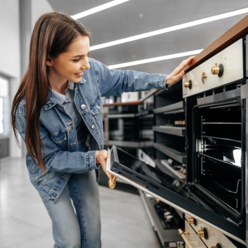 Young woman looking for new electric oven in a shopping mall, close up